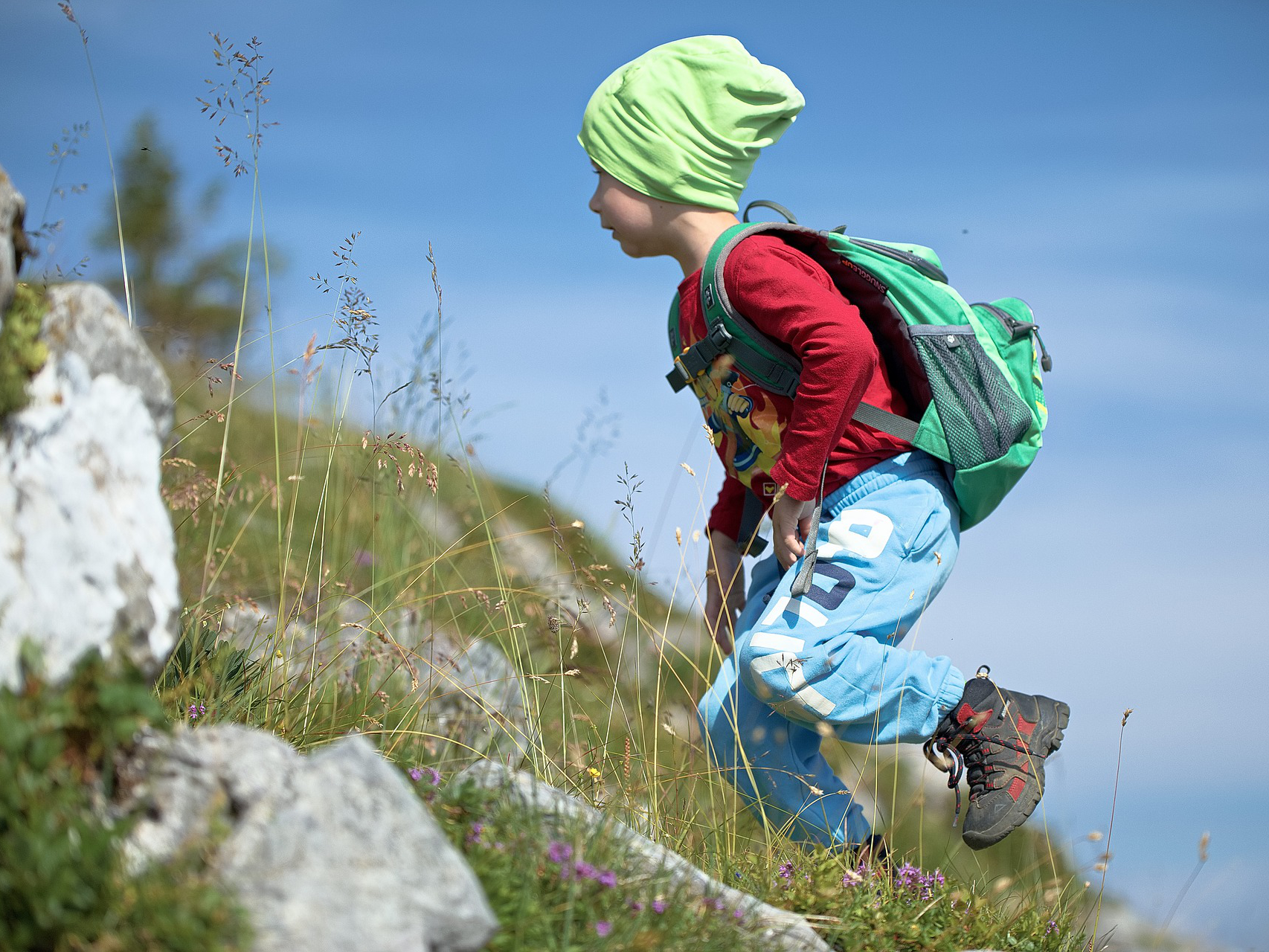 Small boy climbing a hill in a bright green beanie