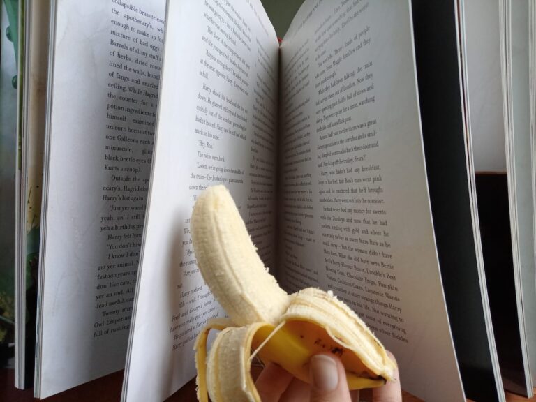 a half-peeled banana in front of an open book.