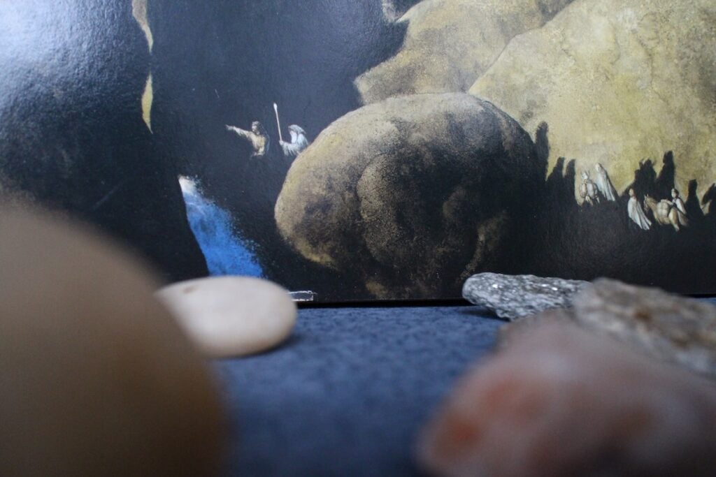 The distant figures of the Fellowship of the Ring make their way through enormous boulders shot-through with waterfalls.