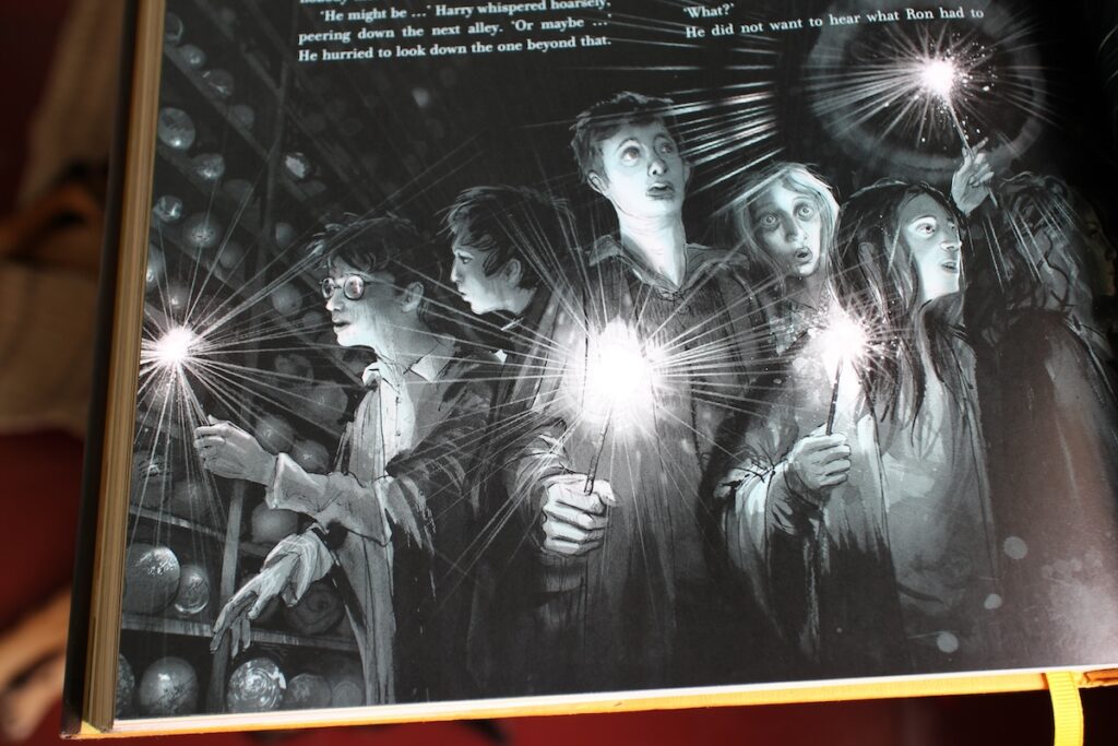 A group of teen witches and wizards shine lights at the ends of their wands while inspecting the bulb-like prophecies on the shelves.