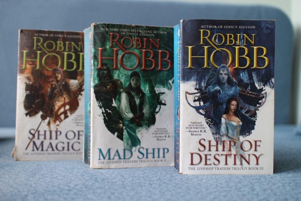 Three books in a row showing mythical ships. This is The Liveship Traders trilogy, excellent adult fantasy books about sentient ships and their human crew.