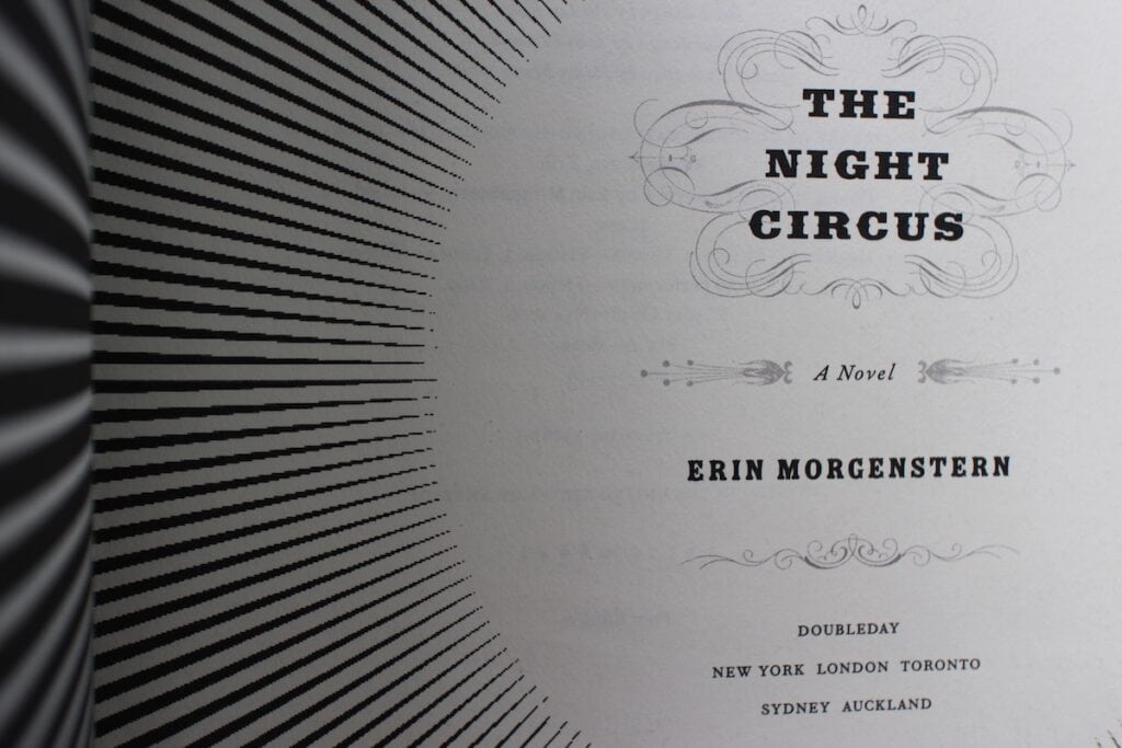 Black and white stripes lead toward the inside cover title of "The Night Circus" by Erin Morgenstern.